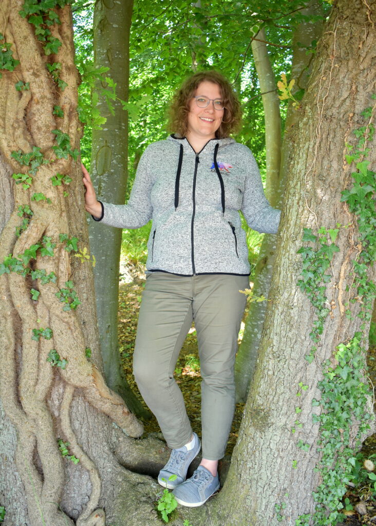 Heilpraktikerin Melanie Möller steht an einem Baum und freut sich.